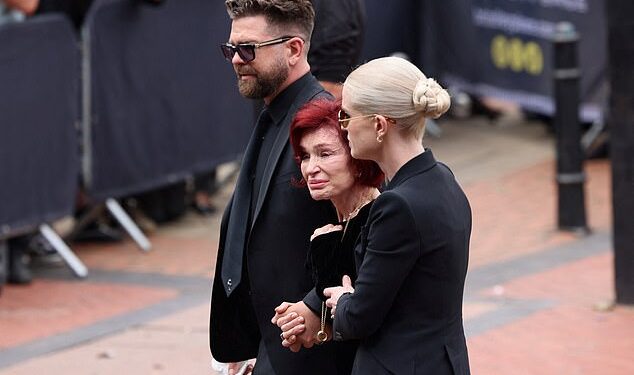 Jack y Kelly sosteniendo a Sharon por los brazos mientras camina