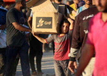 Un niño que lleva una parcela de ayuda, camina por la carretera Salah al-Din, cerca del campo de refugiados de Nusseirat en la franja central de Gaza, utilizado por los palestinos que buscan alimentos para alcanzar un punto de distribución de ayuda establecido por la Fundación Humanitaria de Gaza privada (GHF), el 25 de junio de 2025.