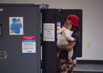 Una mujer sostiene a su bebé mientras vota en una cabina