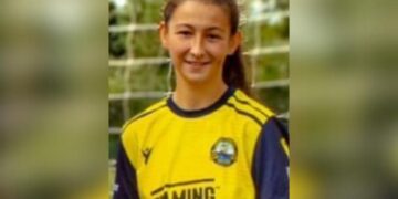 Tiro en la cabeza de una mujer joven en una camiseta de fútbol amarillo.