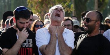 Un padre afligido llora en el funeral de su hijo.
