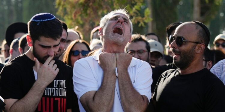 Un padre afligido llora en el funeral de su hijo.