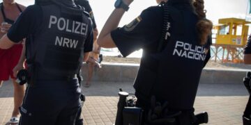 Oficiales de policía alemanes y españoles patrullando una playa.