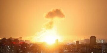 Explosión de misiles balísticos sobre una ciudad por la noche.