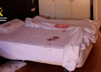 Cama y piso manchado de sangre en una habitación de hotel.