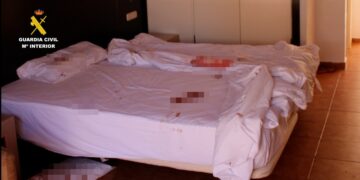 Cama y piso manchado de sangre en una habitación de hotel.