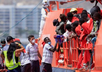 Trabajador de rescate que lleva a un niño migrante desde un barco de la Guardia Costera.