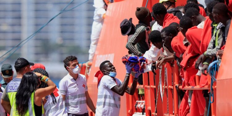 Trabajador de rescate que lleva a un niño migrante desde un barco de la Guardia Costera.