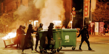 La gente lleva contenedores a la mitad de la calle y los incendia para crear barricadas en Lausana, Suiza
