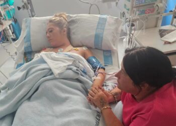 Mujer hospitalizada sosteniendo la mano de su madre.