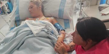 Mujer hospitalizada sosteniendo la mano de su madre.