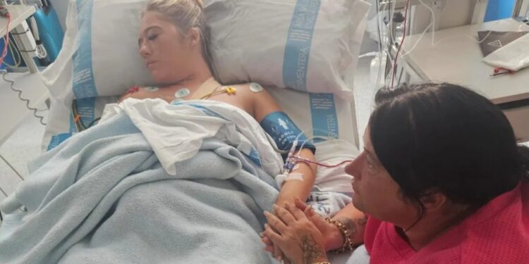 Mujer hospitalizada sosteniendo la mano de su madre.