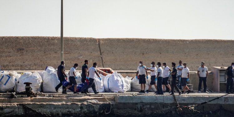 Oficiales de la Guardia Costera que llevan una bolsa de cuerpo en un muelle.