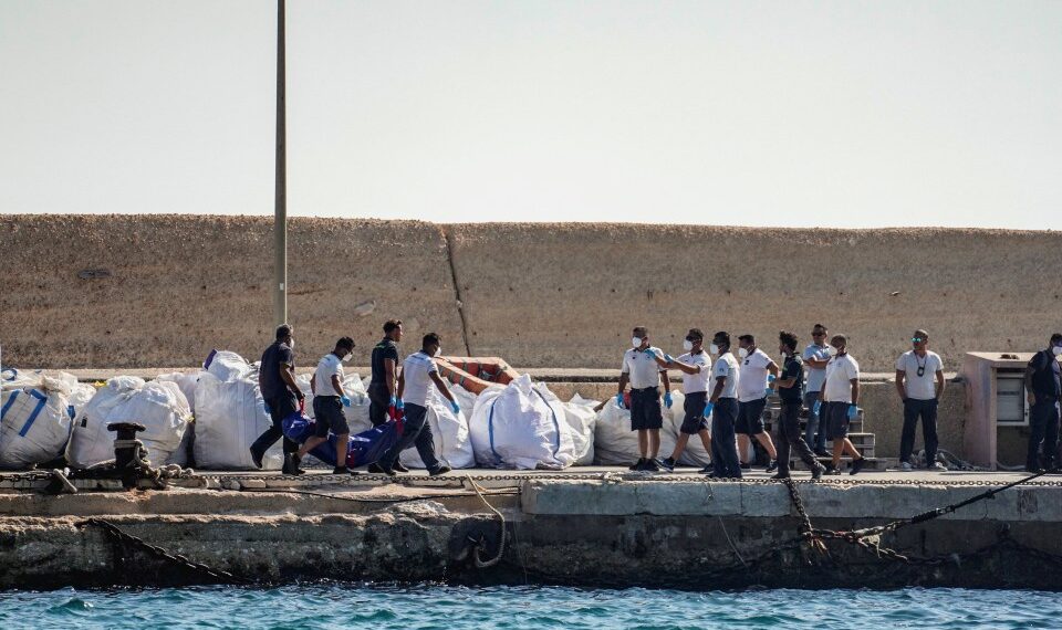 Oficiales de la Guardia Costera que llevan una bolsa de cuerpo en un muelle.