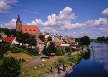 Vista de Eisenhuttenstadt, Alemania, con una iglesia y un río.