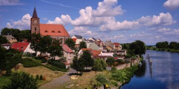 Vista de Eisenhuttenstadt, Alemania, con una iglesia y un río.