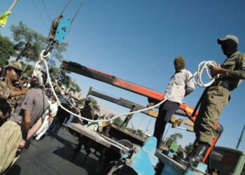 Los soldados iraníes enmascarados y los empleados del gobierno que se preparan para colgar públicamente a un hombre condenado en Shiraz.