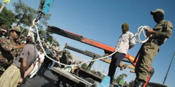 Los soldados iraníes enmascarados y los empleados del gobierno que se preparan para colgar públicamente a un hombre condenado en Shiraz.