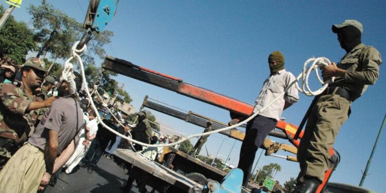 Los soldados iraníes enmascarados y los empleados del gobierno que se preparan para colgar públicamente a un hombre condenado en Shiraz.