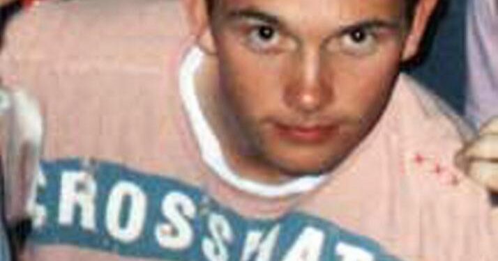 Foto de primer plano de un joven con cabello puntiagudo con una camisa rosa con un diseño azul.