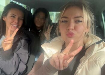 Foto de tres mujeres en un automóvil, haciendo señales de paz.