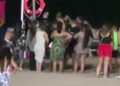 La multitud se reunió en una playa por la noche cerca de un salvavidas.