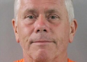 Mugshot de un hombre con un mono naranja.