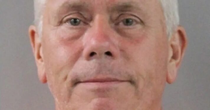 Mugshot de un hombre con un mono naranja.