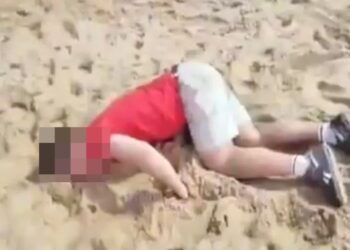 Turista drogado acostado en una playa.