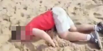 Turista drogado acostado en una playa.