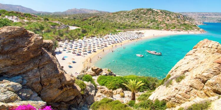 Vai Beach en Creta, Grecia: palmeras, agua turquesa y gente que se relaja en la costa arenosa.