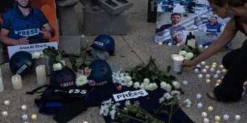 La gente sostiene fotos, pone flores y velas ligeras durante una vigilia fuera de la sede de Fox News y NBC News en Washington, DC, el 11 de agosto de 2025, en honor a periodistas asesinados en Gaza, incluidos Anas al-Sharif y sus colegas.