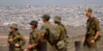 Soldados israelíes que observan edificios destruidos en la Franja de Gaza.