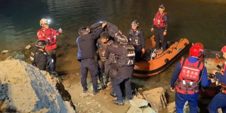 Los trabajadores de rescate ayudando a un buzo cerca de un cuerpo de agua.