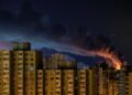 El humo se eleva sobre los edificios de apartamentos de Kyiv por la noche después de ataques de misiles rusos.