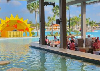 Barra de natación en un complejo con una gran piscina y una estructura de sol amarillo.