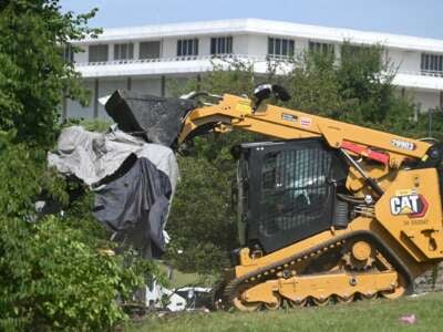 Los trabajadores de la ciudad de DC desmantelan las carpas y eliminan las pertenencias personales durante un barrido de un campamento para personas sin hogar en el vecindario inferior de Foggy en Washington, DC, el 14 de agosto de 2025.