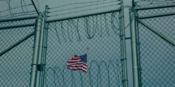 Una bandera estadounidense vuela detrás de la esgrima de alambre en el edificio de la Oficina de Comisiones Militares el 27 de junio de 2023, en la Bahía de Guantánamo, Cuba.