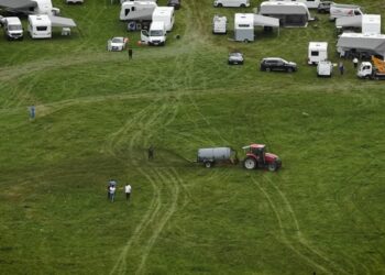 Vista aérea de un tractor que extiende el estiércol en un campo con varias caravanas estacionadas cerca.