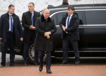 Vladimir Putin con guardaespaldas cerca de un automóvil.