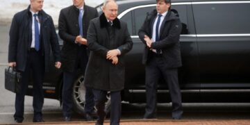 Vladimir Putin con guardaespaldas cerca de un automóvil.