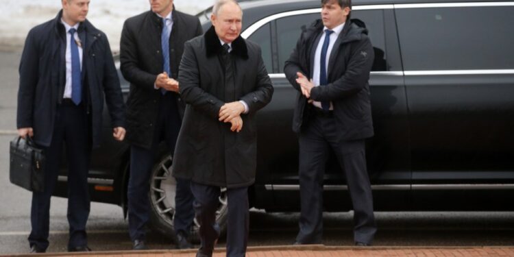 Vladimir Putin con guardaespaldas cerca de un automóvil.