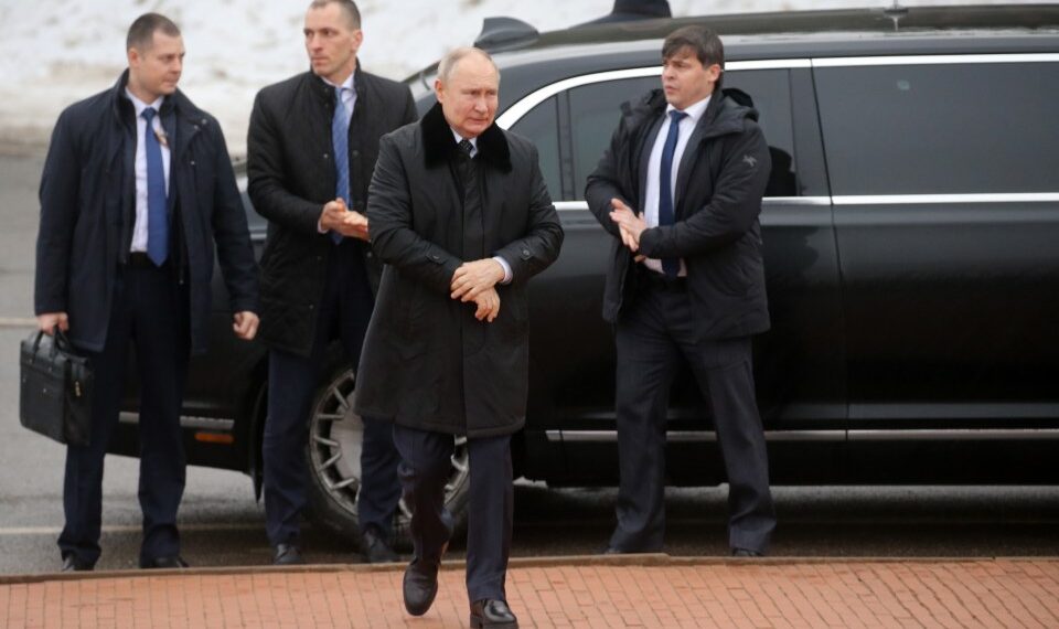 Vladimir Putin con guardaespaldas cerca de un automóvil.