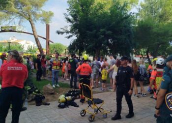 La gente se reunió afuera de un hotel después de un incendio, personal de emergencia presente.