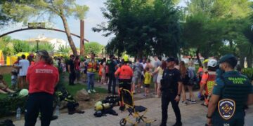 La gente se reunió afuera de un hotel después de un incendio, personal de emergencia presente.