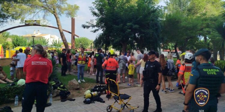 La gente se reunió afuera de un hotel después de un incendio, personal de emergencia presente.