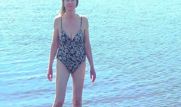 Mujer en un traje de baño vadeando en un lago.