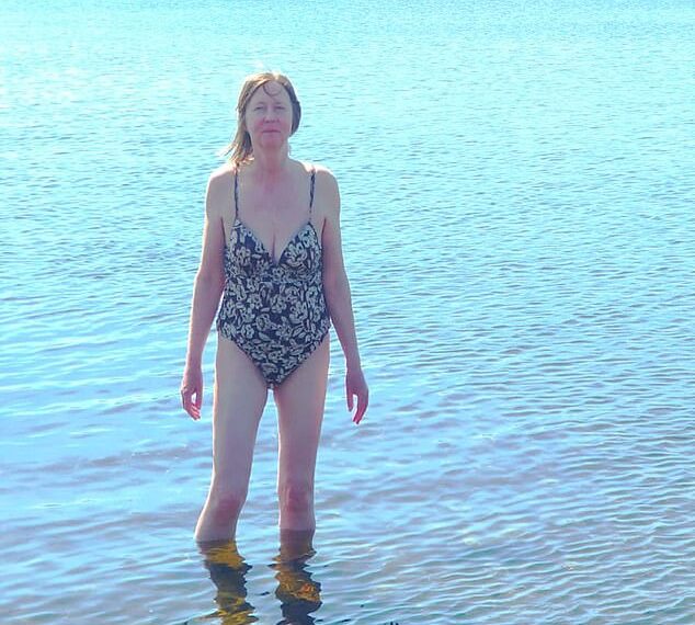 Mujer en un traje de baño vadeando en un lago.