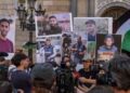 Un portavoz de los medios de comunicación en Barcelona habla en una conferencia de prensa con personas con retratos de los periodistas de Al Jazeera recientemente asesinados en Gaza por el ejército israelí.