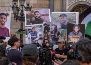 Un portavoz de los medios de comunicación en Barcelona habla en una conferencia de prensa con personas con retratos de los periodistas de Al Jazeera recientemente asesinados en Gaza por el ejército israelí.